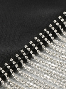 Makro-Detail von silbernen Strassfransen und Ketten an einem schwarzen Bandage-Kleid