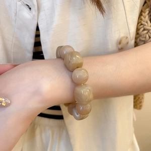 Détail d'un bracelet en perles acryliques beige crème avec une texture marbrée unique