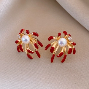 Detail of vintage 18k gold plated firework earring with red enamel and pearl accent