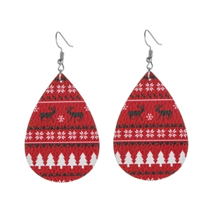 Close-up of teardrop leather earrings with red elk and snowflake Christmas patterns