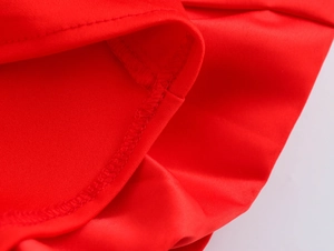 Detailed close-up of high-quality sewing stitches and red fabric texture on the hemline