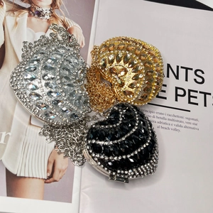 Three heart-shaped rhinestone evening bags in gold, silver, and black on a fashion magazine