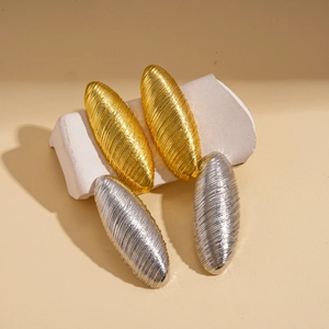 Brushed metal oval earrings in gold and silver finish on a minimalist stone base
