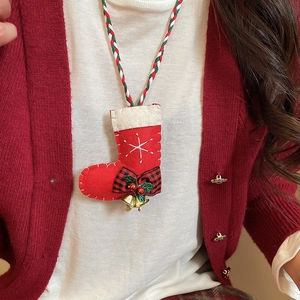 Detail of a Christmas plush sock pendant necklace with tiny bells and checkered bow