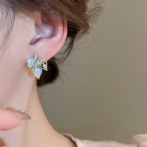 French vintage gold leaf earrings with blue enamel and sparkling crystals worn on ear
