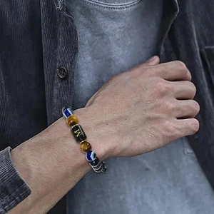 Macro detail of male wrist wearing tiger eye stone bracelet with letter M engraving