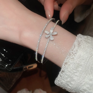 Close-up of double-layer zircon flower bangle in silver on a wrist with dark background
