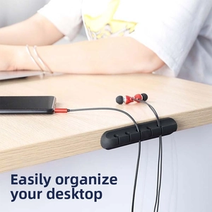Black 5-slot silicone cable organizer securing cords on a wooden office desk edge