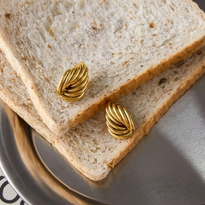Gros plan de boucles d'oreilles croissant en acier 18K doré sur du pain