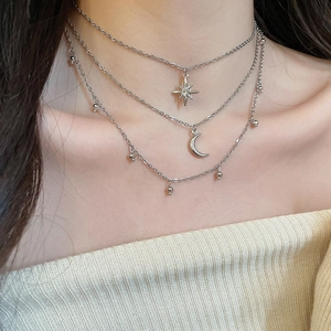 Detail of layered silver necklaces featuring a rhinestone star and crescent moon pendant