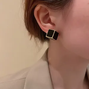 Boucles d'oreilles cubes chic noir et or portées par un mannequin en gros plan