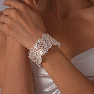 Gros plan détaillé du large bracelet ouvert argenté avec motifs floraux ajourés complexes