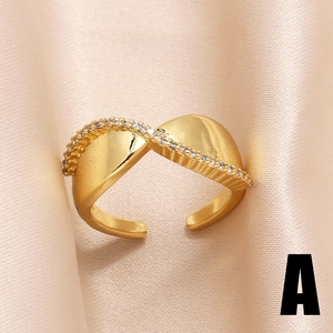 Anello ondulato placcato oro 18k con zirconi luccicanti su sfondo di seta beige