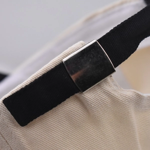 Detail shot of the adjustable silver metal buckle and strap on a cotton baseball cap