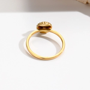 Macro shot of gold stainless steel ring featuring unique gear-shaped top and polished finish