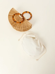 Detail of semicircular bamboo handbag featuring amber acrylic handles and beige inner pouch