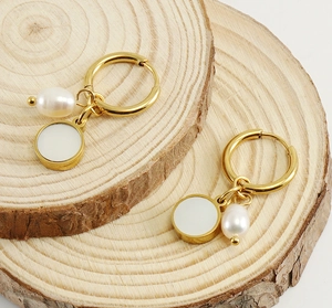 Detailed macro view of gold-plated hoop earrings with baroque pearls on a wooden base
