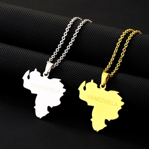 Detailed close-up of gold and silver Venezuela map pendants on textured black background