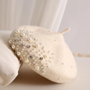 Detail of cream beige wool beret featuring elegant pearls and sparkling rhinestones