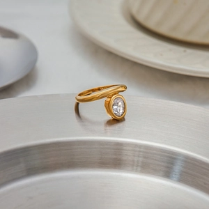 Close-up of 18K gold plated ring featuring an oval-cut clear zircon on a metal tray