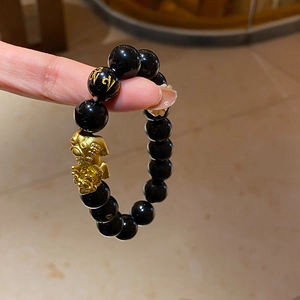 Detailed shot of black obsidian beads with golden Pixiu charm and mantra engraving