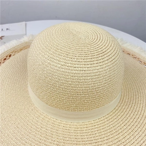 Dettaglio di un cappello di paglia a tesa larga con nastro elegante e bordi sfilacciati