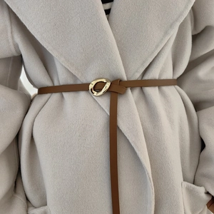 Detail of a thin brown leather belt with a gold geometric buckle on a grey wool coat