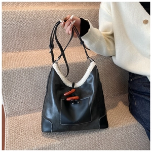 Detail of black leather tote bag with white plush trim and decorative brown horn button