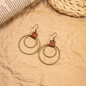 Detail of vintage bohemian earrings with bronze metal rings and brown leather accents