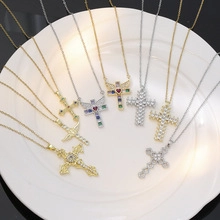 Flat lay of multiple gold and silver cross necklaces with colorful rhinestones in a white dish
