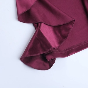 Detailed close-up of dark red satin fabric edge showing precise stitching and smooth silk texture