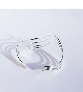 Detailed view of layered silver-tone wavy bangle with minimalist geometric design lines