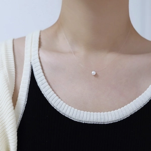 Detail of a natural round white pearl on a transparent invisible fishing line necklace