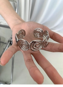 Detail showing silver spiral hollow design and artistic texture of the open cuff bracelet