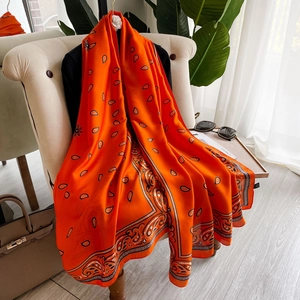 Elegante sciarpa arancione in finta seta con motivo paisley su una sedia imbottita