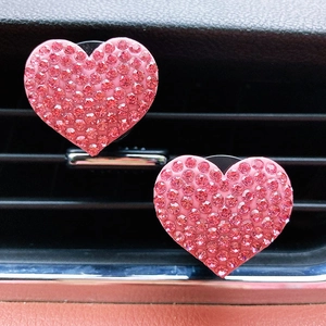 Macro shot of two pink rhinestone heart-shaped car air vent aromatherapy clips