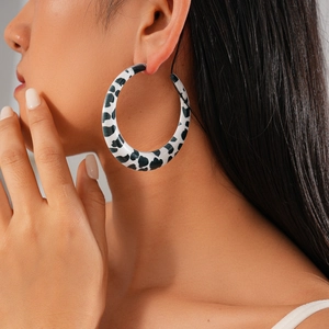 Close-up of large round hoop earring featuring a black and white cow print finish