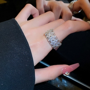 Close-up of a silver-toned wide hollow flower ring with zircon stones on model's hand