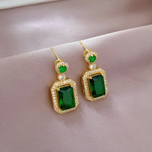 Elegant gold titanium earrings with rectangular emerald stones and diamond halo design