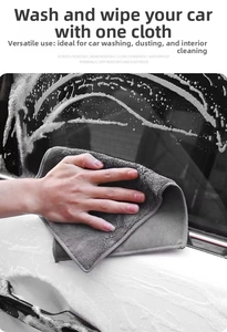 Detailed view of thick microfiber towel cleaning foam off white car window and body
