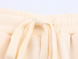 Dettaglio ravvicinato del tessuto in maglia con coulisse regolabile su pantaloncini beige
