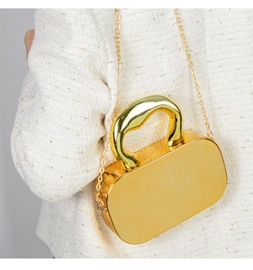 Detail of gold mirror acrylic box bag featuring a sleek handle and fine chain strap