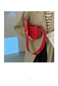 Detail view of red PU leather saddle bag with gold adjustment buckle and wide strap