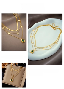 Detailed view of layered gold titanium necklace with emerald square and waterdrop pendants