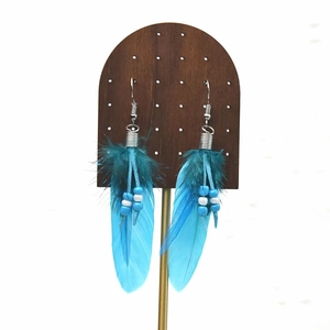 Detail of bohemian long feather tassel earrings with blue beads on wooden display stand