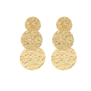 Macro detail of golden stacked earrings with layered circles and hammered metal texture