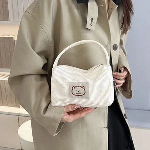 Minimalist white corduroy tote bag with cute bear patch, shown with khaki trench coat