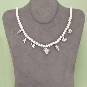 Elegant white pearl necklace with silver sea shell and starfish charms on display