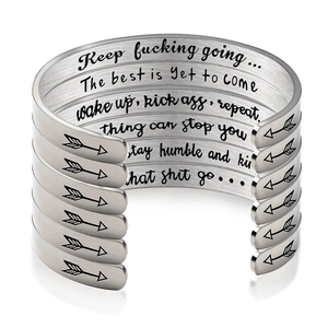 Stack of silver stainless steel cuff bracelets with engraved inspirational quotes