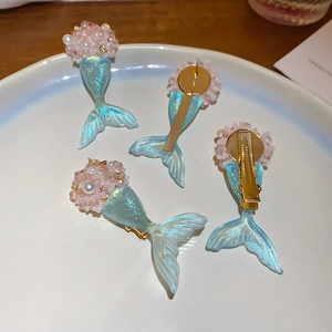 Detailed view of resin pearl flower and fishtail hair clips and earrings set on a tray